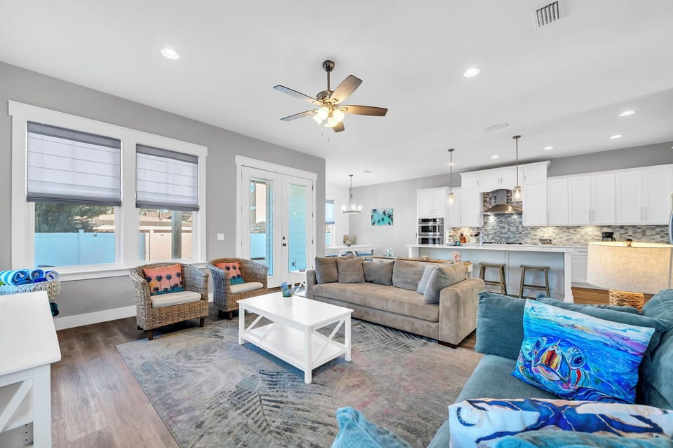 Bright white walls, coastal blue accents, and an open floor plan that lets the beach-house air flow freely — light pours in and the whole space lifts with it.