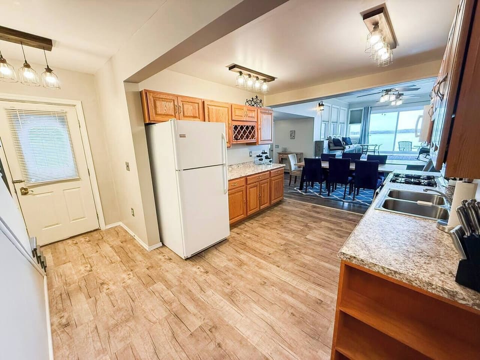 The kitchen has everything you need — full fridge, built-in wine rack, and cooking amenities — with the dining table and Cayuga Lake framed perfectly at the end of the room.