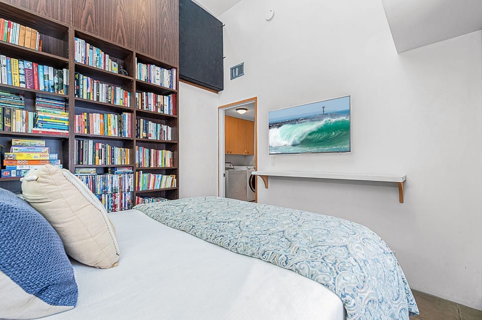 Cozy guest bedroom with a queen-size bed surrounded by extensive built-in bookshelves
                