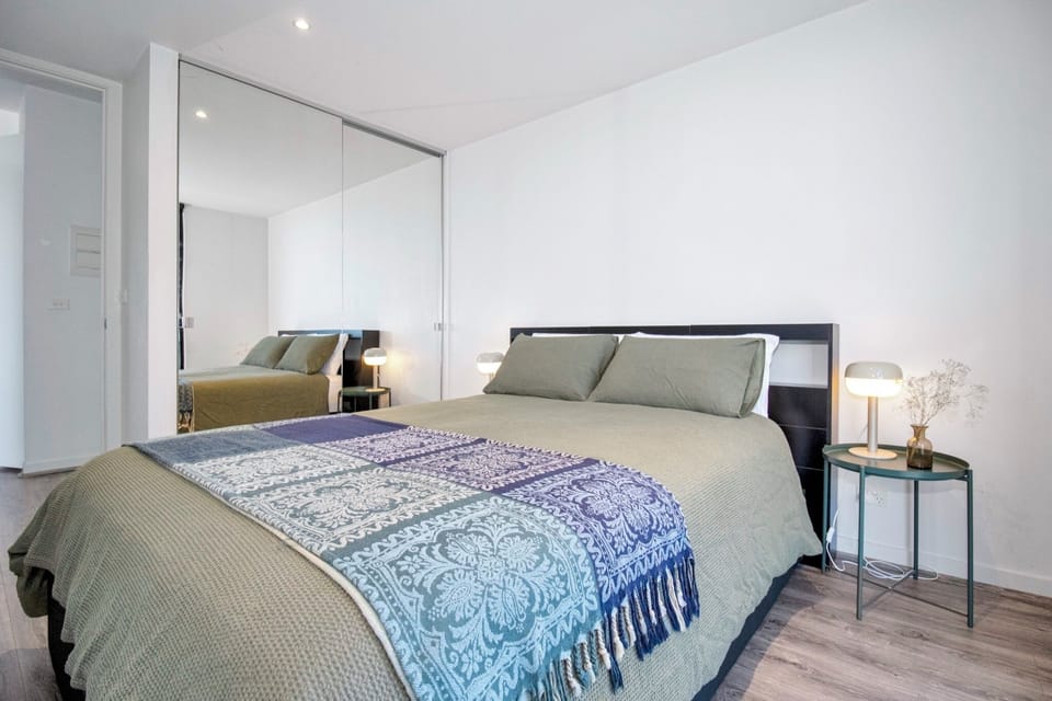 Bright modern bedroom with mirrored wardrobe and cozy bedside lighting