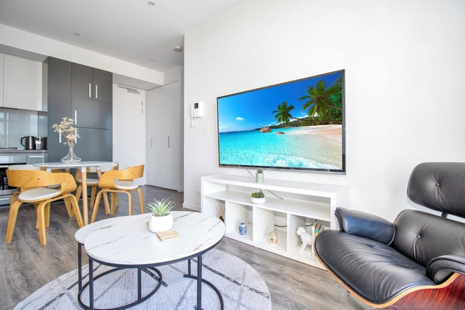Bright modern lounge with large TV, dining nook, and sleek open layout