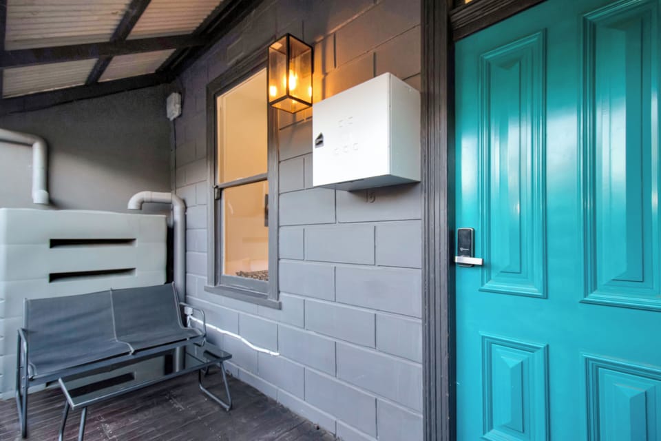 Welcoming covered entry with bold turquoise door and modern lighting