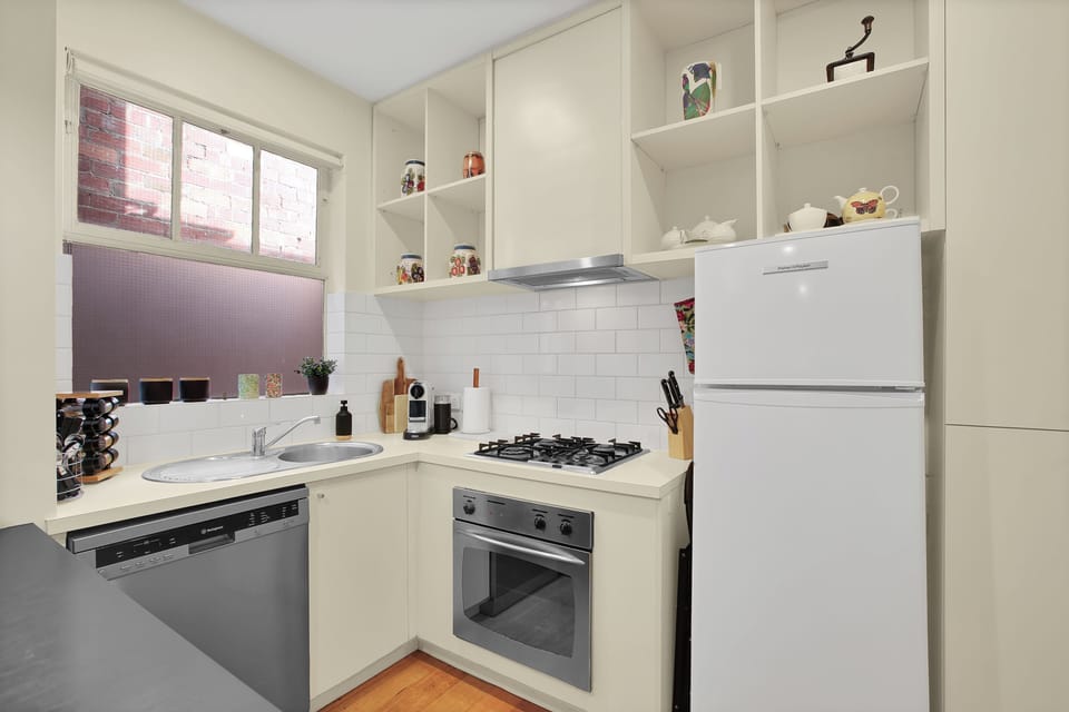 Bright compact kitchen with gas stove, dishwasher and coffee setup