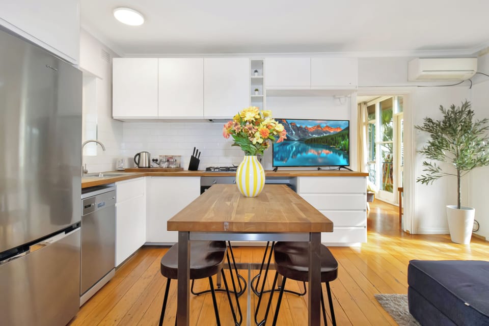 Bright modern kitchen with dining table, AC, and warm timber floors
