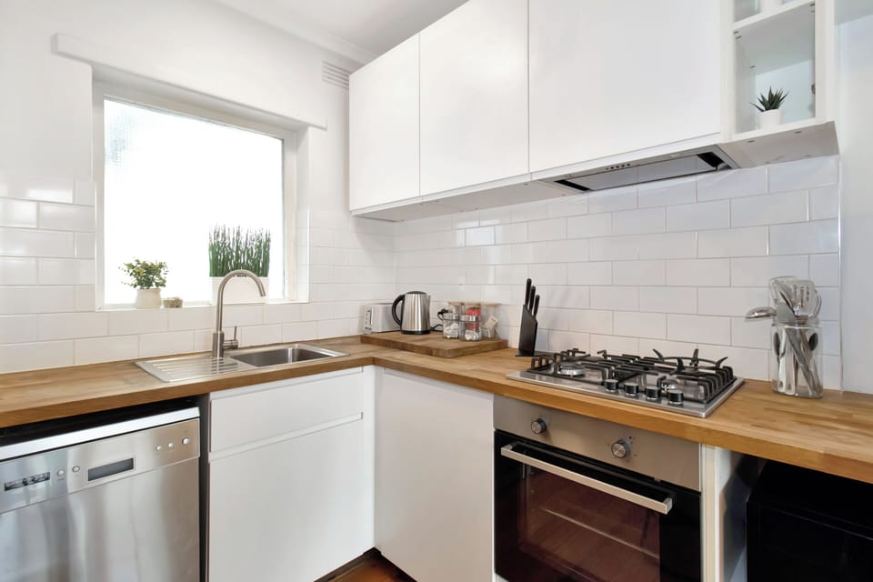 Bright modern kitchen with gas cooktop, wood counters, and natural light