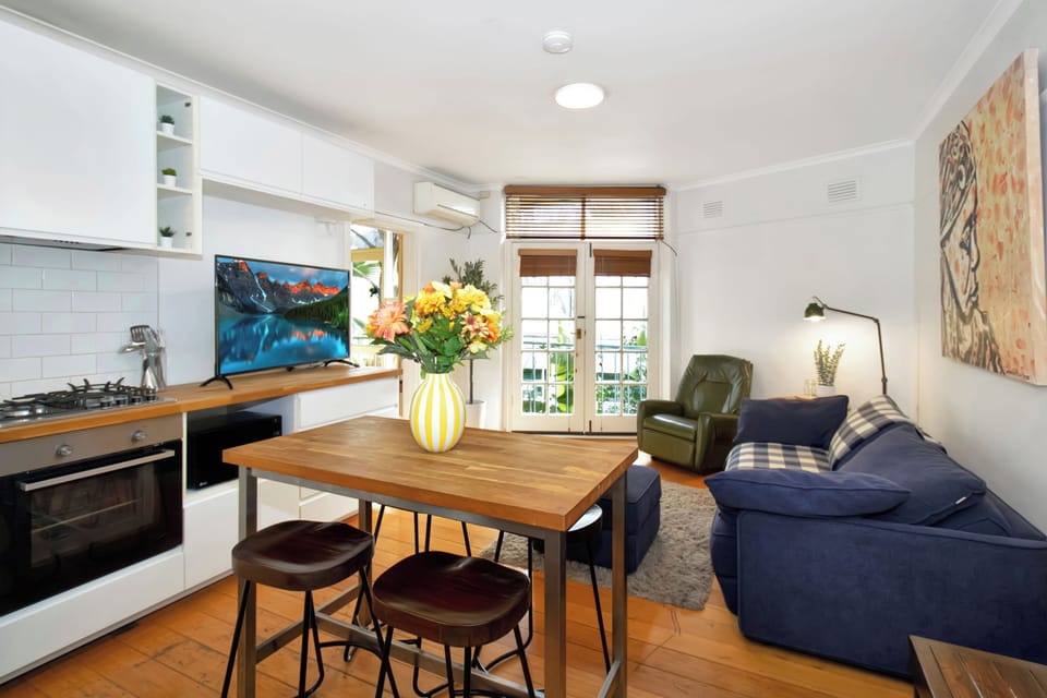 Bright open-plan studio with full kitchen, dining table, and balcony access