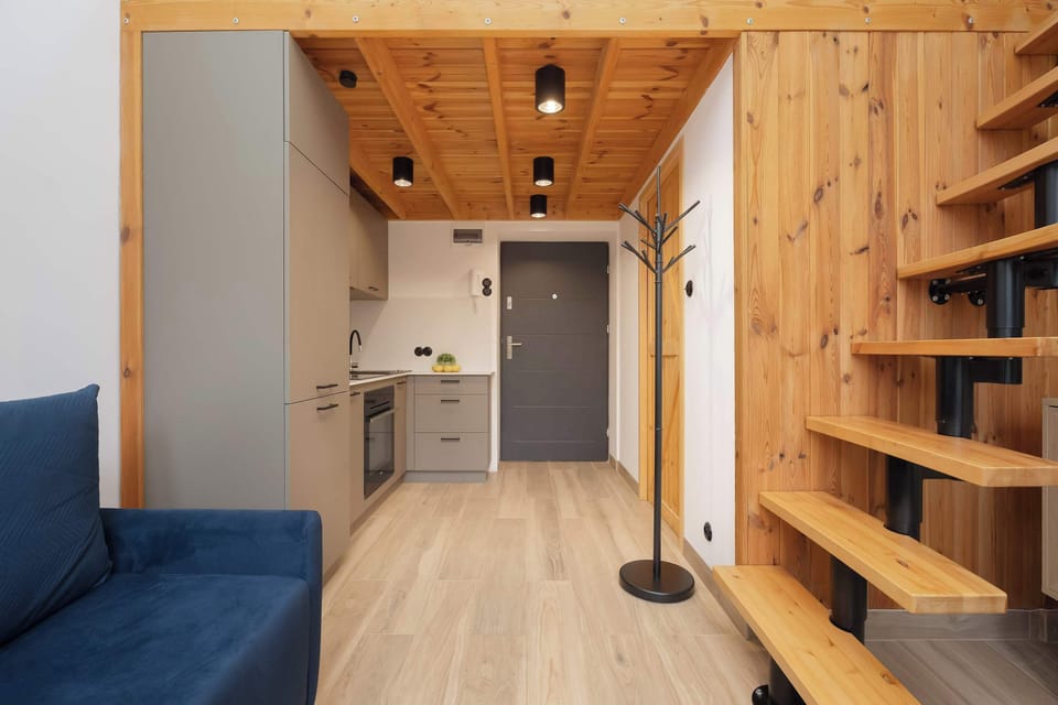 Entrance area with a modern kitchenette and wooden stairs to the mezzanine.