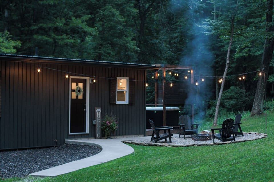 Cozy woodland cabin with hot tub, fire pit, and glowing string lights