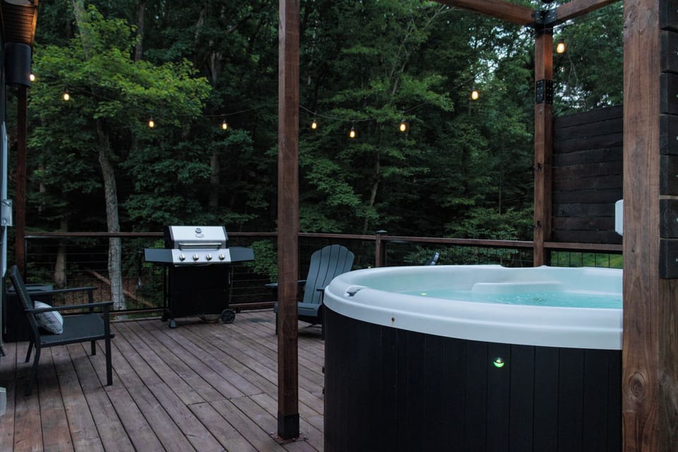 Private forest-view hot tub deck with grill and cozy string lights