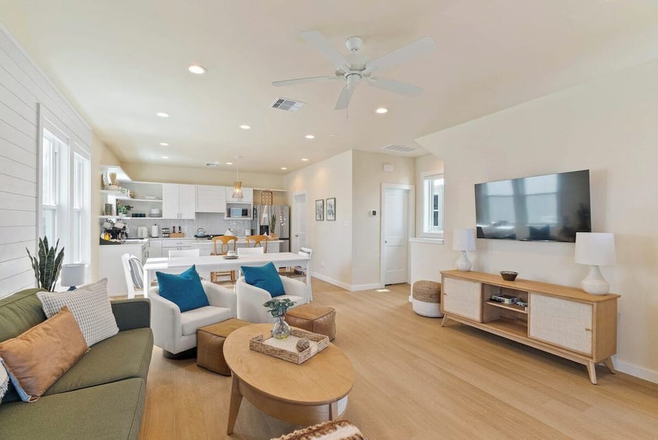 Another view of the bright and open living space with large smart TV, cozy seating, large dining area, and kitchen — perfect for gathering and relaxing together.