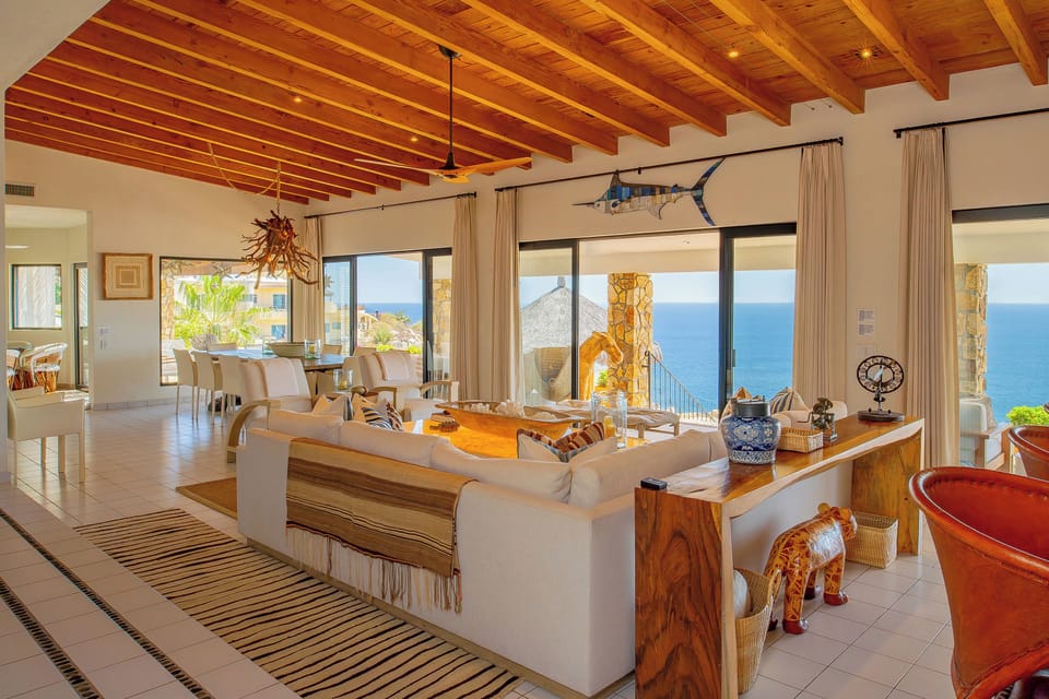 Unwind in your open-concept living space where exposed beam ceilings meet stunning ocean views through floor-to-ceiling windows.