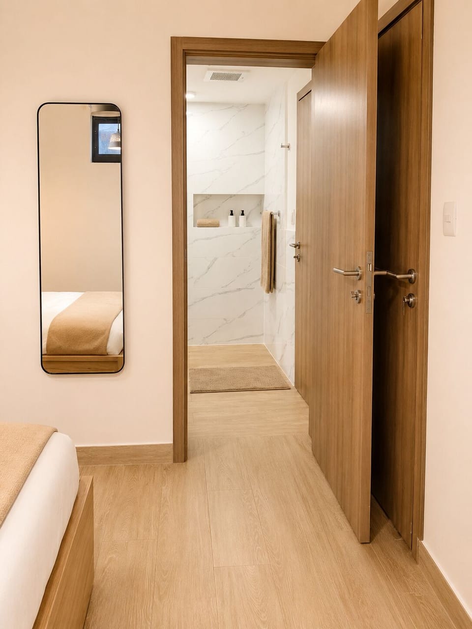 Elegant bathroom with marble tiles and a walk-in shower, adjacent to a cozy bedroom.