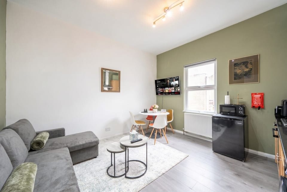 Open-plan living with smart TV, dining and full kitchen in one bright space.