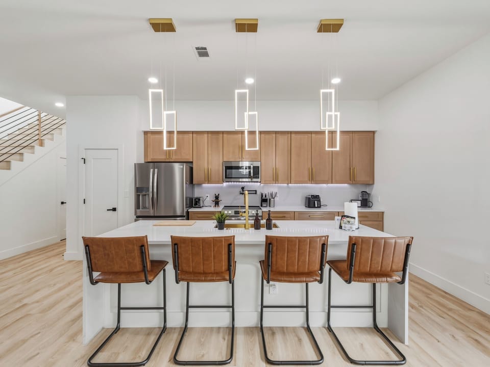 Gather around your spacious kitchen island with modern bar seating for four. Stylish pendant lighting and warm wood accents create the perfect atmosphere for morning coffee or evening conversation.