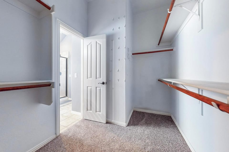 A spacious walk-in closet with custom wood shelving provides plenty of organized storage for your wardrobe and personal items, keeping everything within easy reach during your stay.