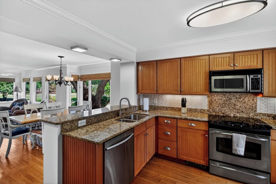 Your fully-equipped kitchen with granite countertops, modern appliances, and open layout makes meal prep a breeze while you enjoy views of the lush green surroundings.