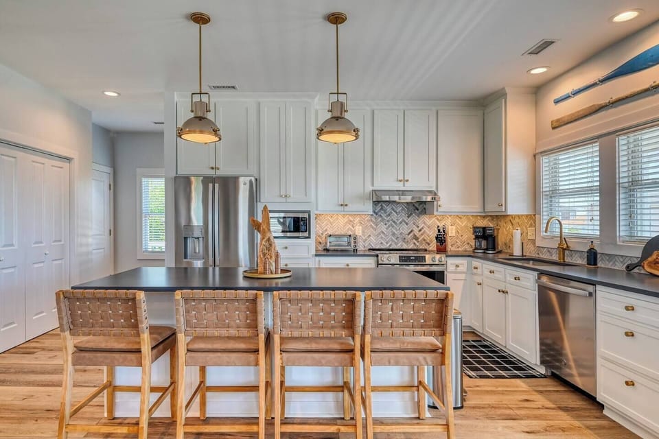 Modern kitchen with island seating and stainless appliances.