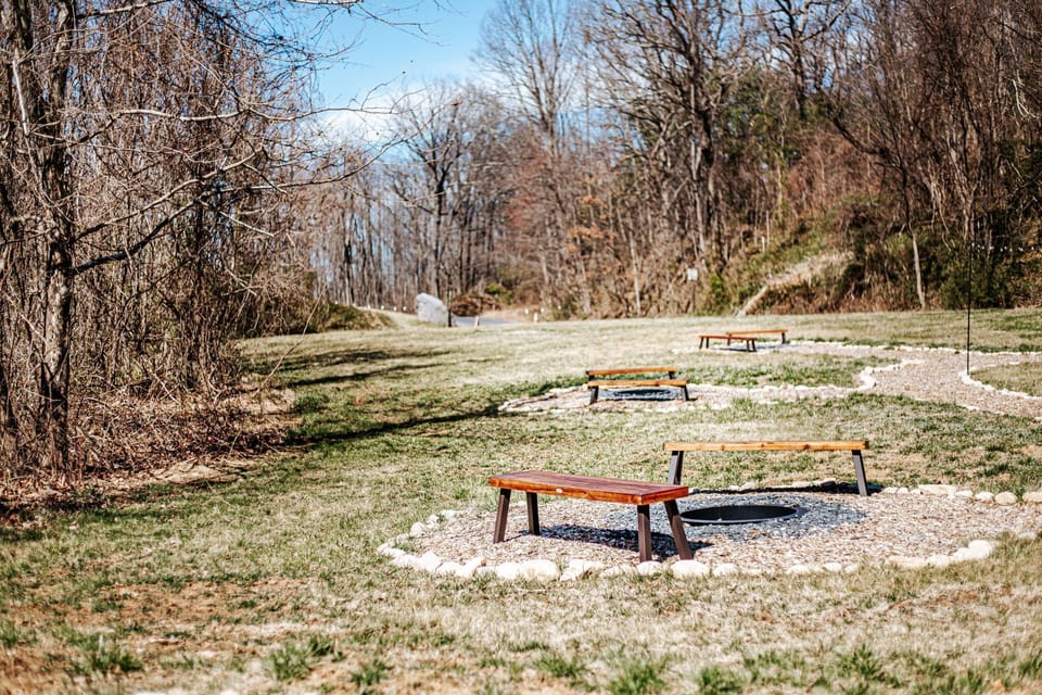 Multiple fire pits, each with its own bench, create a cozy atmosphere in a peaceful, natural setting.