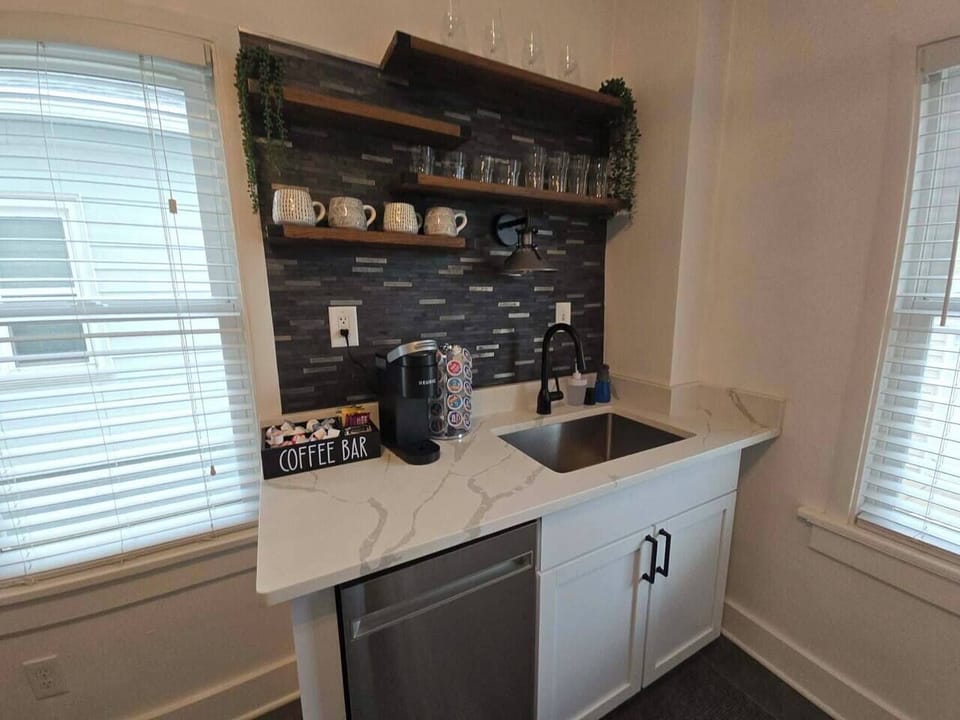 Modern coffee bar with open shelving, sink, and sleek designer finishes