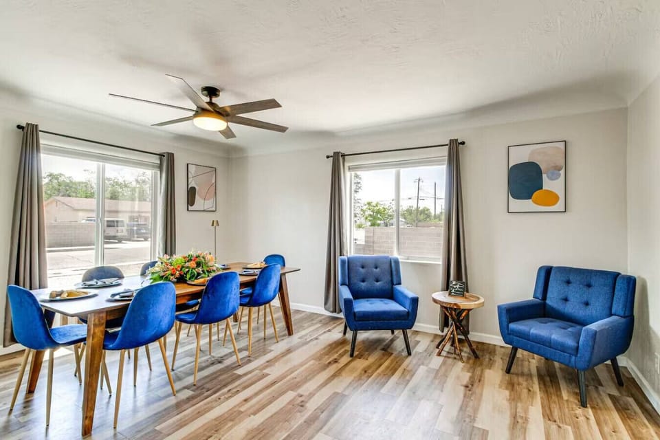 Dining area flows right into the living room — bright, open, and built for groups. Blue velvet chairs, hardwood floors, and everyone at the table together.