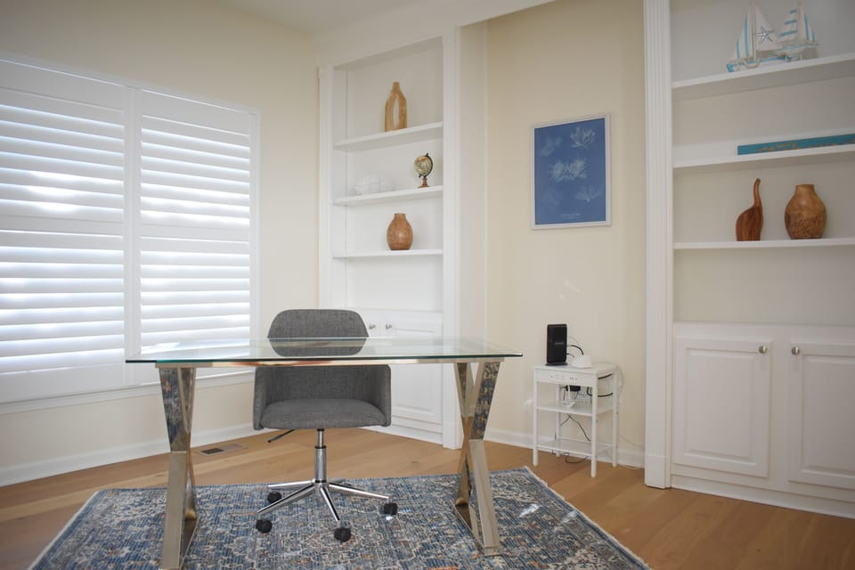 Bright home office with glass desk, natural light, and stylish built-ins