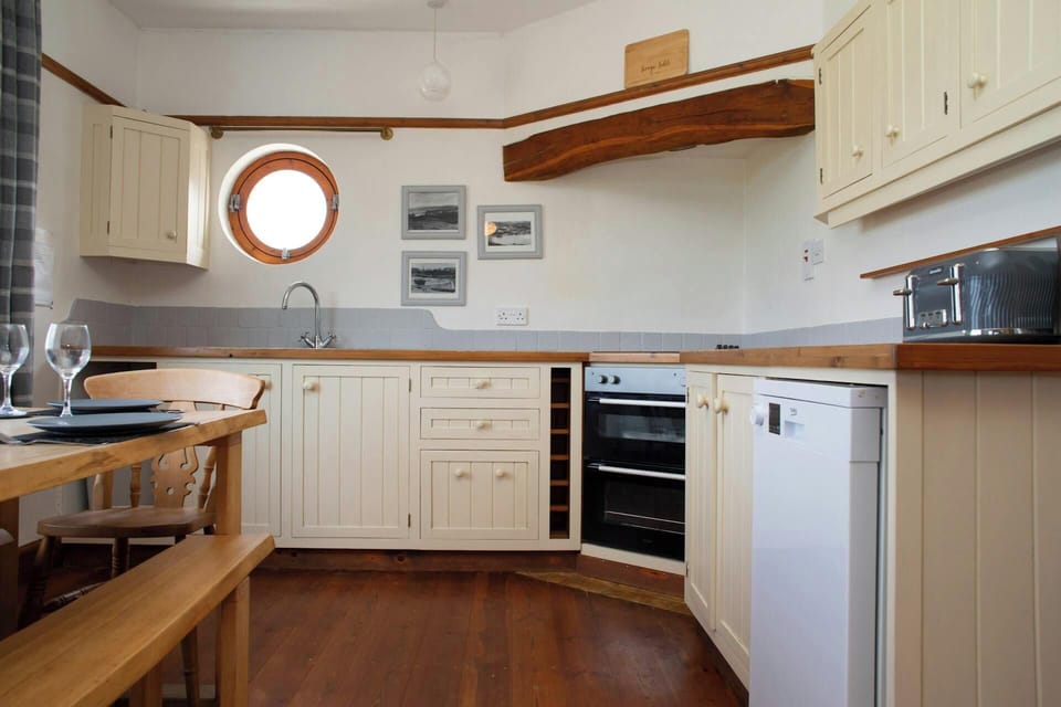 Cream kitchen with wooden worktops, round window and built-in oven