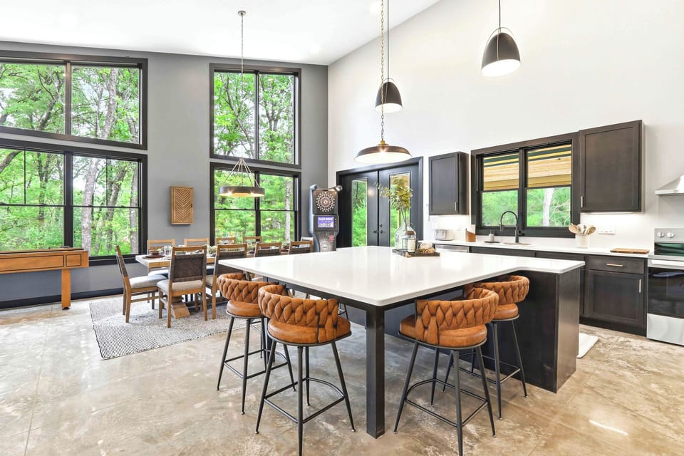 Start the day at the oversized island or linger over dinner beneath soaring windows, where modern design and wooded views make gathering feel effortless.