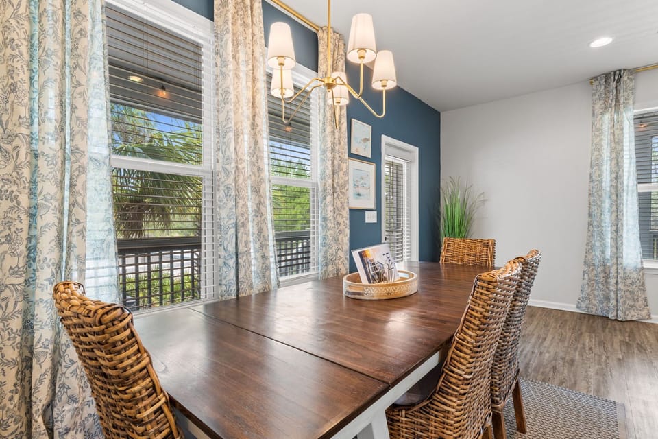 Bright dining space with large windows, woven chairs, and stylish decor