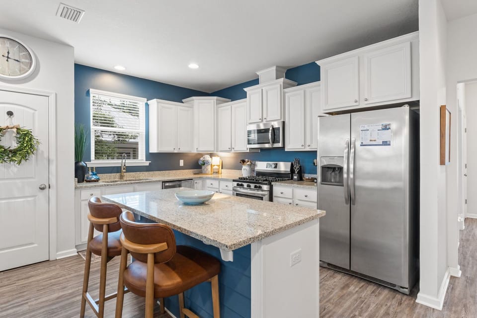 Bright modern kitchen with granite island, seating, and stainless appliances