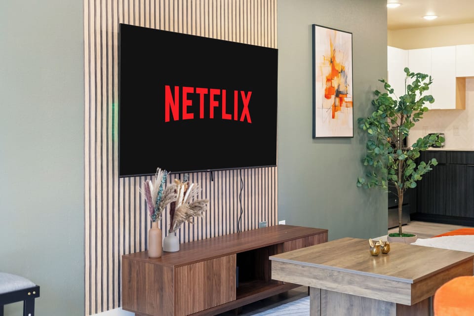 Wall-mounted smart TV with streaming access, a warm wood feature wall, and a sleek media console, creating a comfortable setup for relaxed evenings in the living room.