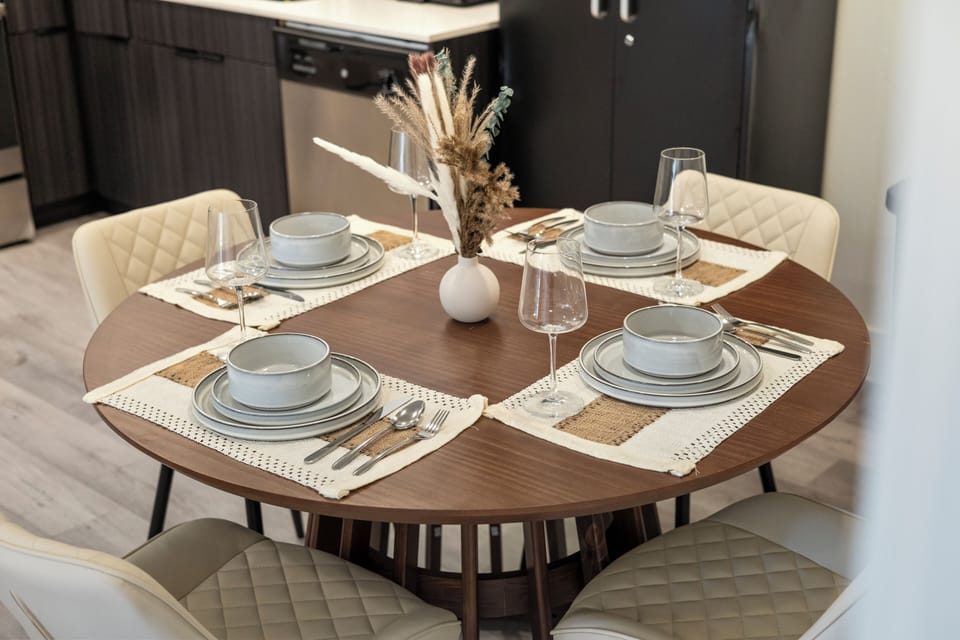 Round dining table set for six with cushioned chairs and warm decor, creating an inviting space for shared meals, conversation, or planning the day together.