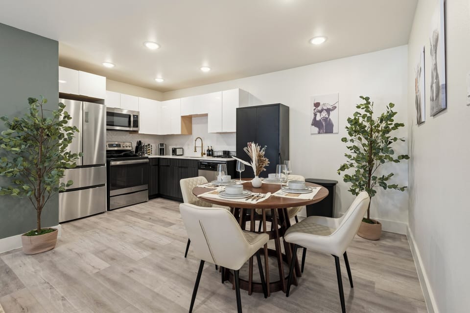 Open dining area with seating for four beside a modern kitchen, creating a bright and convenient space for shared meals and relaxed time together.