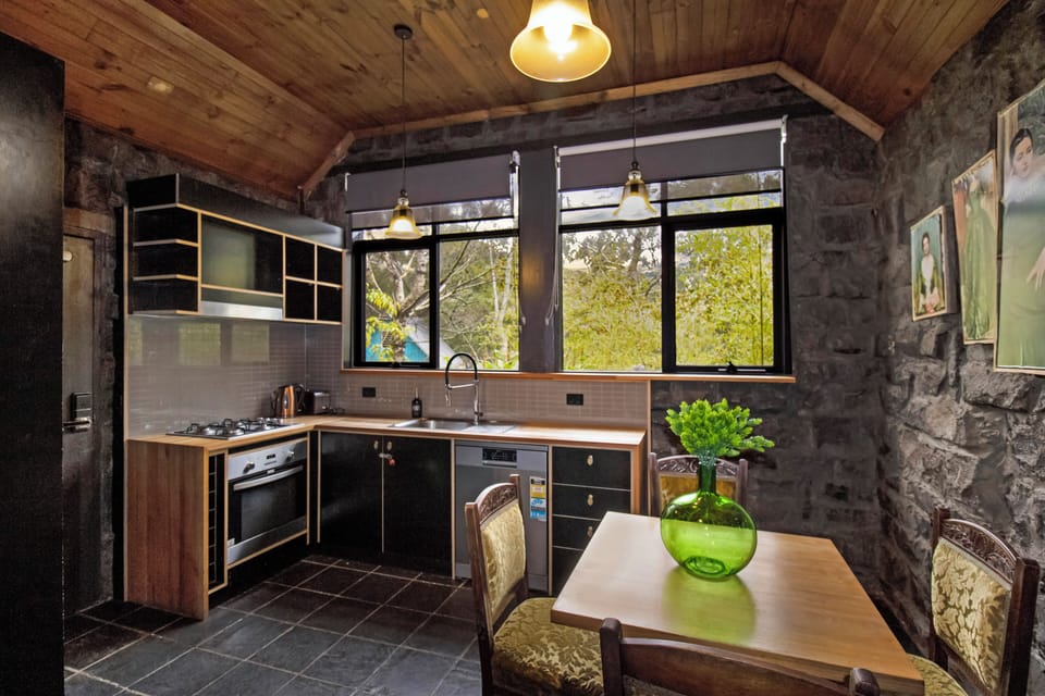 Rustic stone kitchen with vaulted wood ceiling and bright garden views