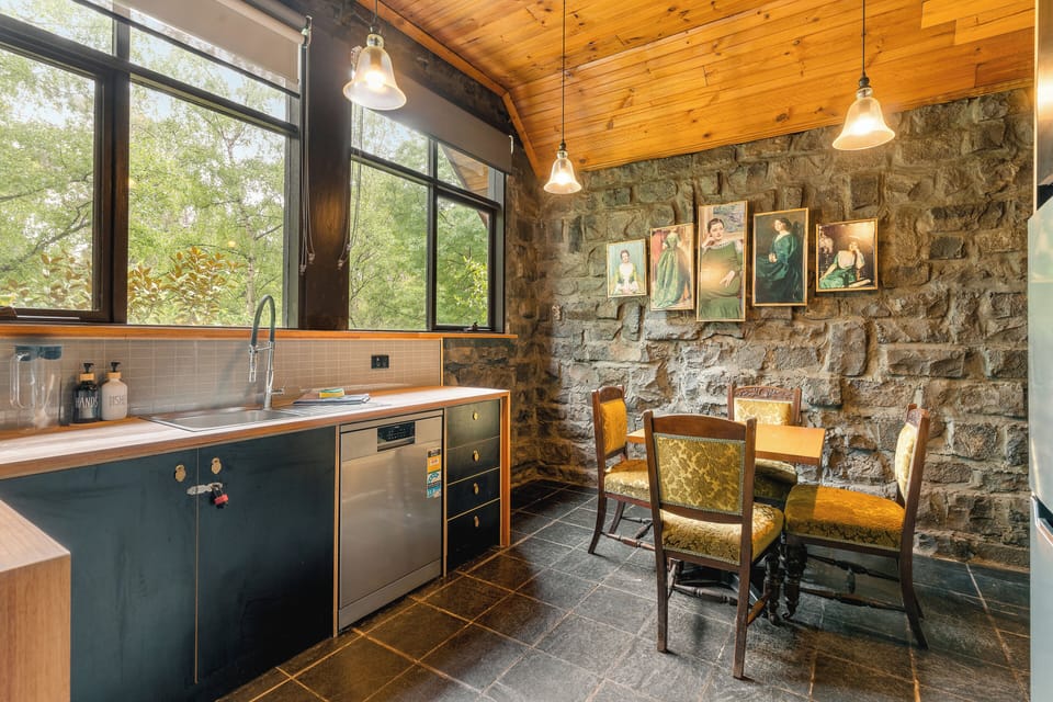 Rustic stone-wall kitchen with greenery views and cozy dining nook