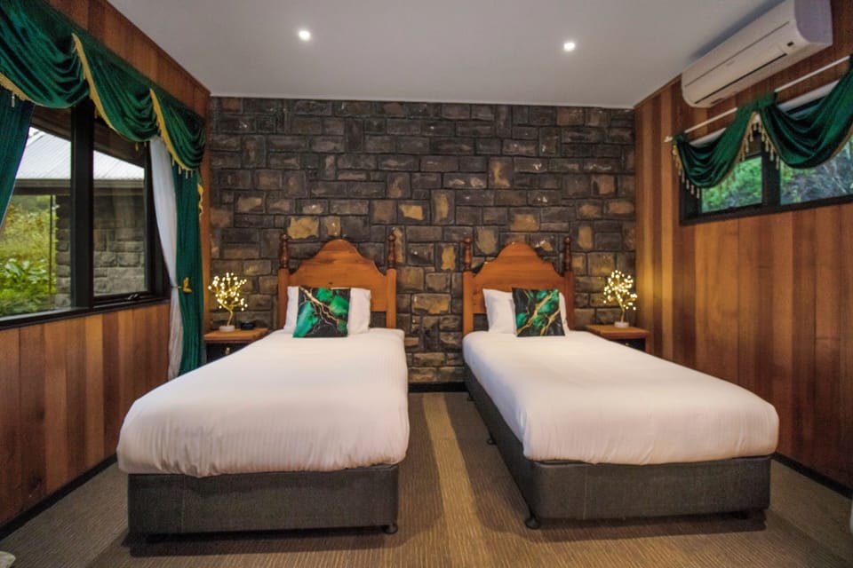 Cozy twin bedroom with stone wall, wood accents, and lodge-style charm
