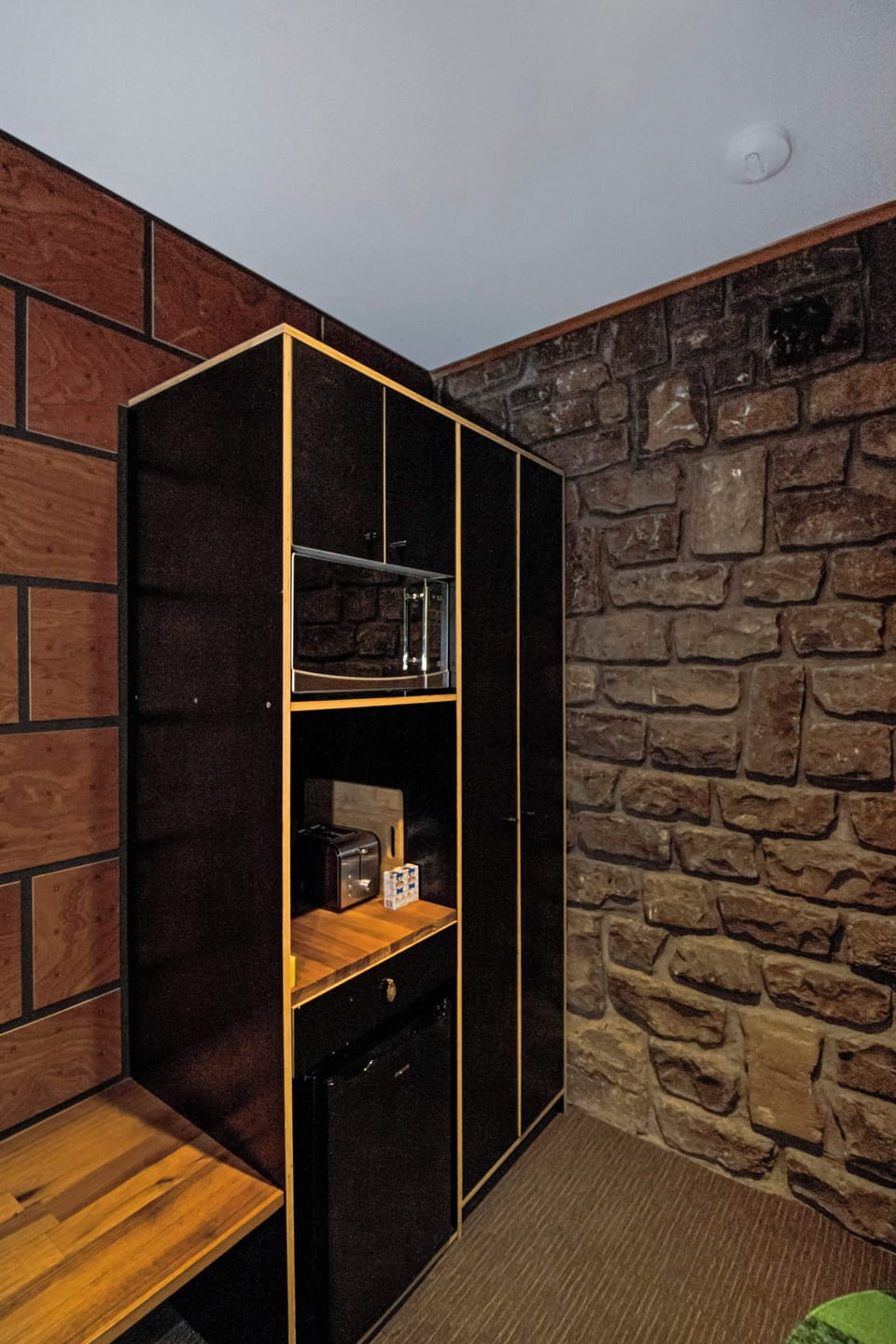 Cozy kitchenette nook with mini fridge, microwave, and rustic stone wall