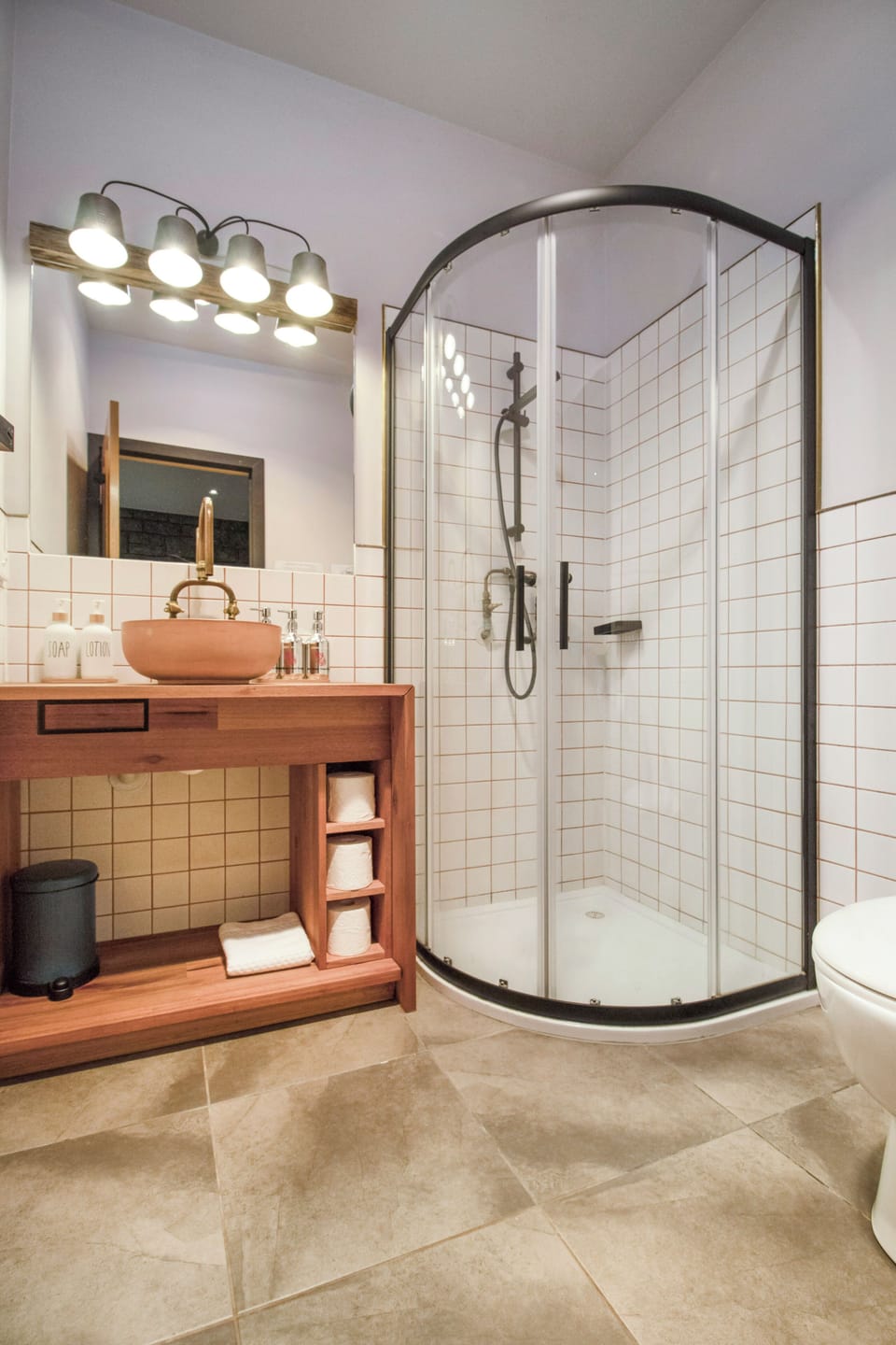 Modern bathroom with curved glass shower and warm wood vanity