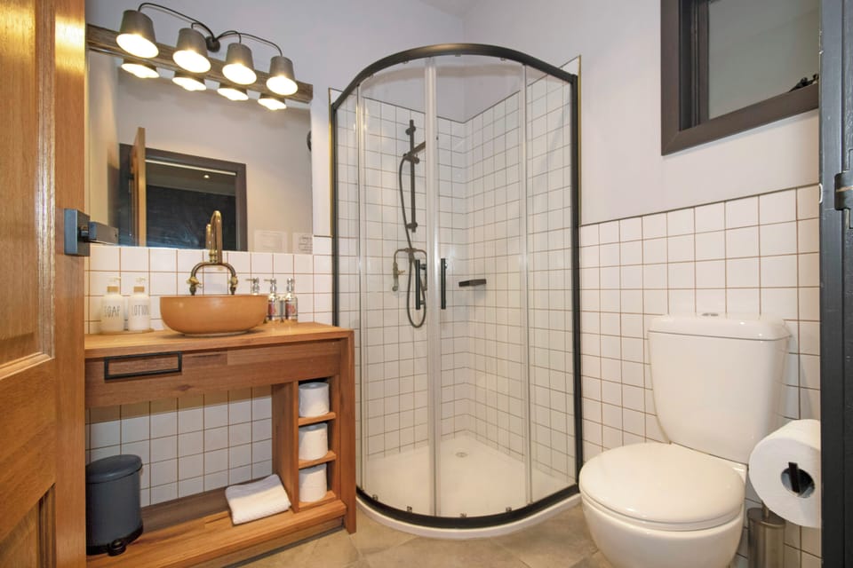 Modern bathroom with glass shower, wood vanity, and sleek black accents