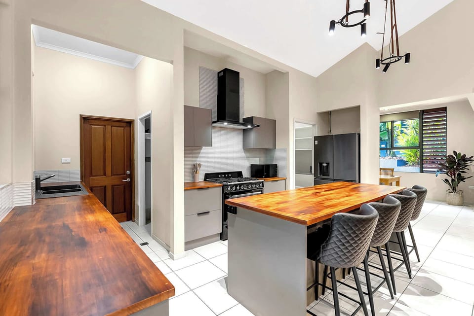 Gather around the kitchen island with a coffee or grazing platter, where generous bench space and bar seating keep conversation flowing while meals come together.