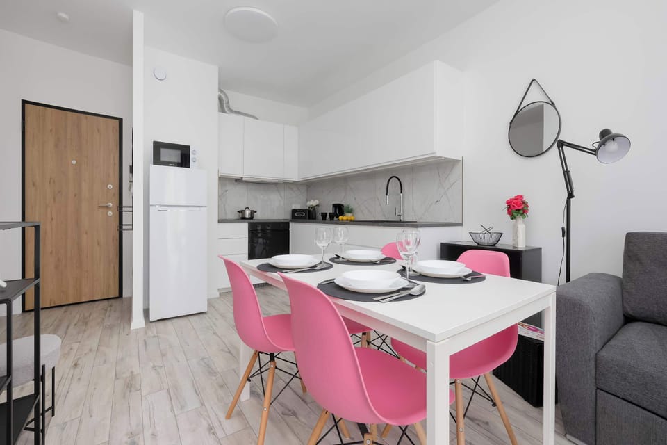 Stylish dining area with a white table and vibrant pink chairs.