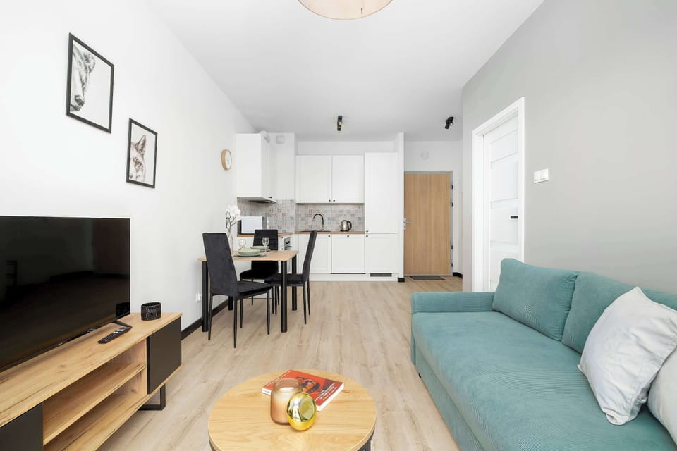 This view of the living area highlights the open-concept design connecting the kitchen directly to the lounging zone. A light teal sofa and a minimalist wooden coffee table anchor the room.