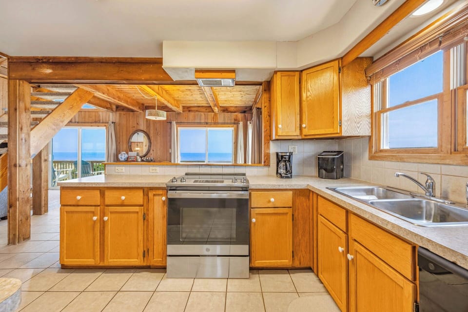 Prepare your favorite meals in this bright kitchen with ocean views, exposed wooden beams, and all the essentials for your vacation stay.