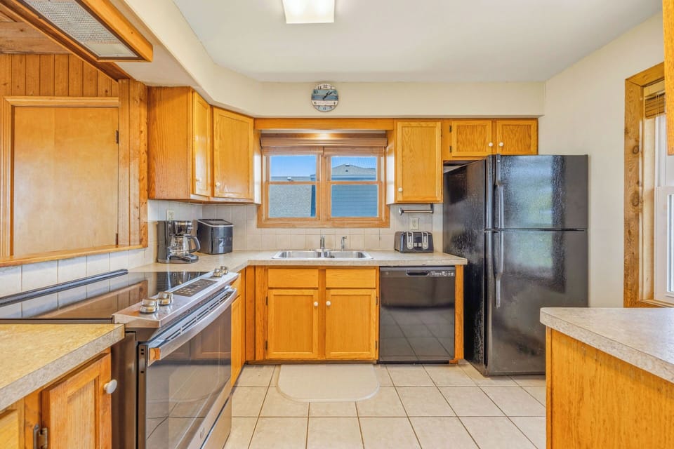 Your fully equipped kitchen awaits, with warm wood cabinets, modern appliances, and a charming window view that brings natural light into your cooking space.