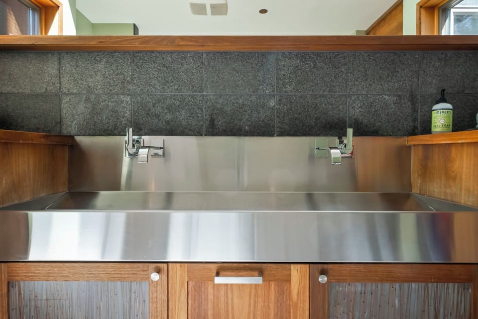 A sleek stainless steel double sink with modern fixtures sits beneath stylish gray tiled backsplash, blending industrial charm with warm wood cabinetry for your kitchen convenience.