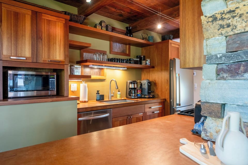 Your fully-equipped kitchen features warm wood cabinetry, stainless appliances, and a spacious island for preparing meals and gathering with loved ones in a beautifully designed space.