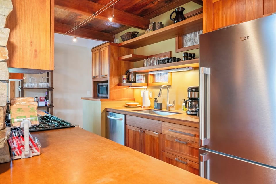 Step into your fully equipped kitchen with warm wood finishes, stainless steel appliances, and open shelving. Everything you need to prepare meals during your stay.