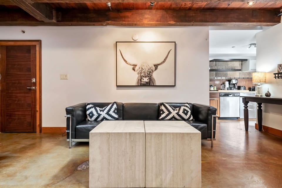 Sink into the plush leather sofa beneath rustic wooden beams, where modern comfort meets authentic character. The open layout flows seamlessly into your kitchen, creating a welcoming space to relax after exploring.