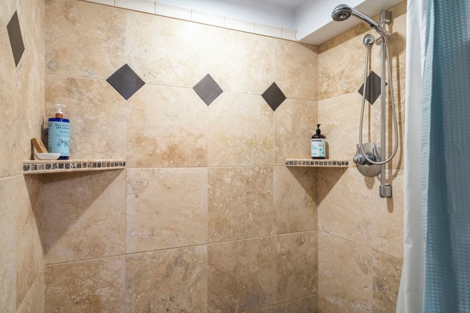 Rinse away the day in your beautifully tiled walk-in shower, complete with built-in corner shelves for your essentials and a handheld showerhead for added comfort.