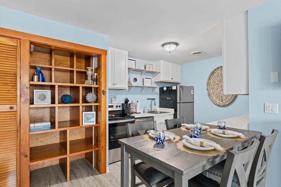 The spacious dining set sits adjacent to a fully equipped kitchen featuring modern black appliances.