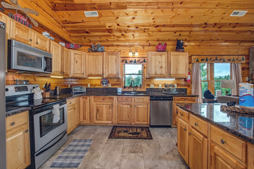 Picture yourself whipping up breakfast in this fully-equipped cabin kitchen, warmed by natural wood and granite counters, with mountain views framing your morning coffee.